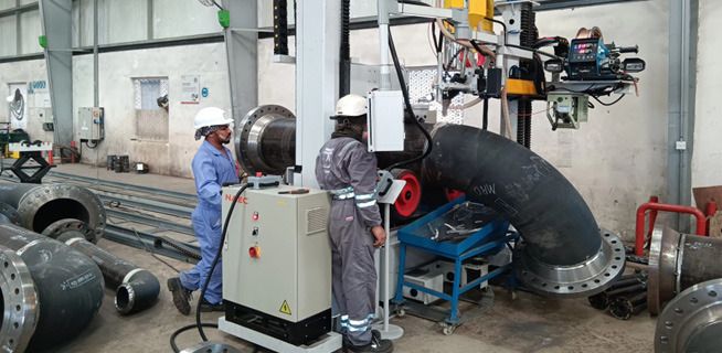Operators at a pipe welding machine